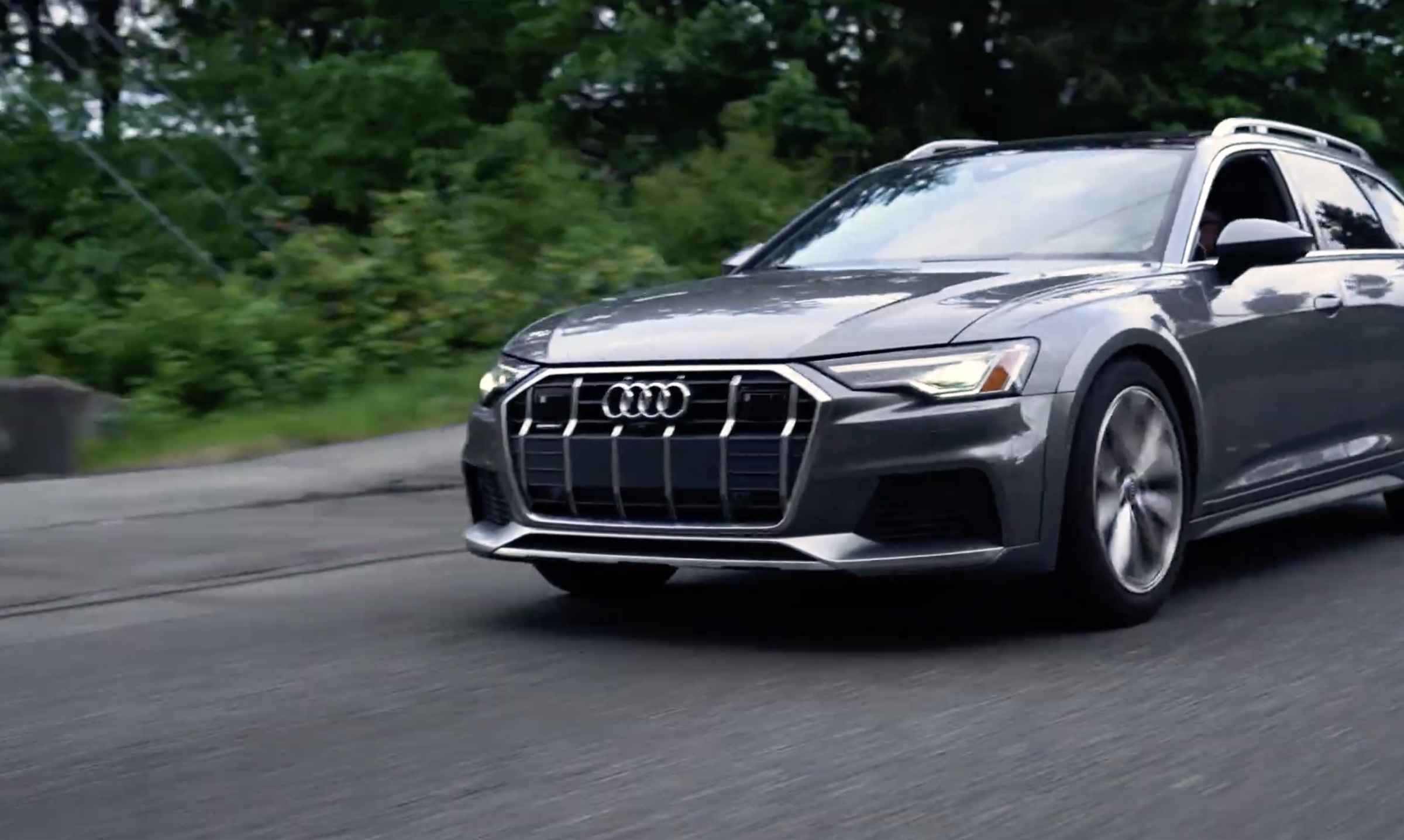 Gray Audi driving along a tree-lined road